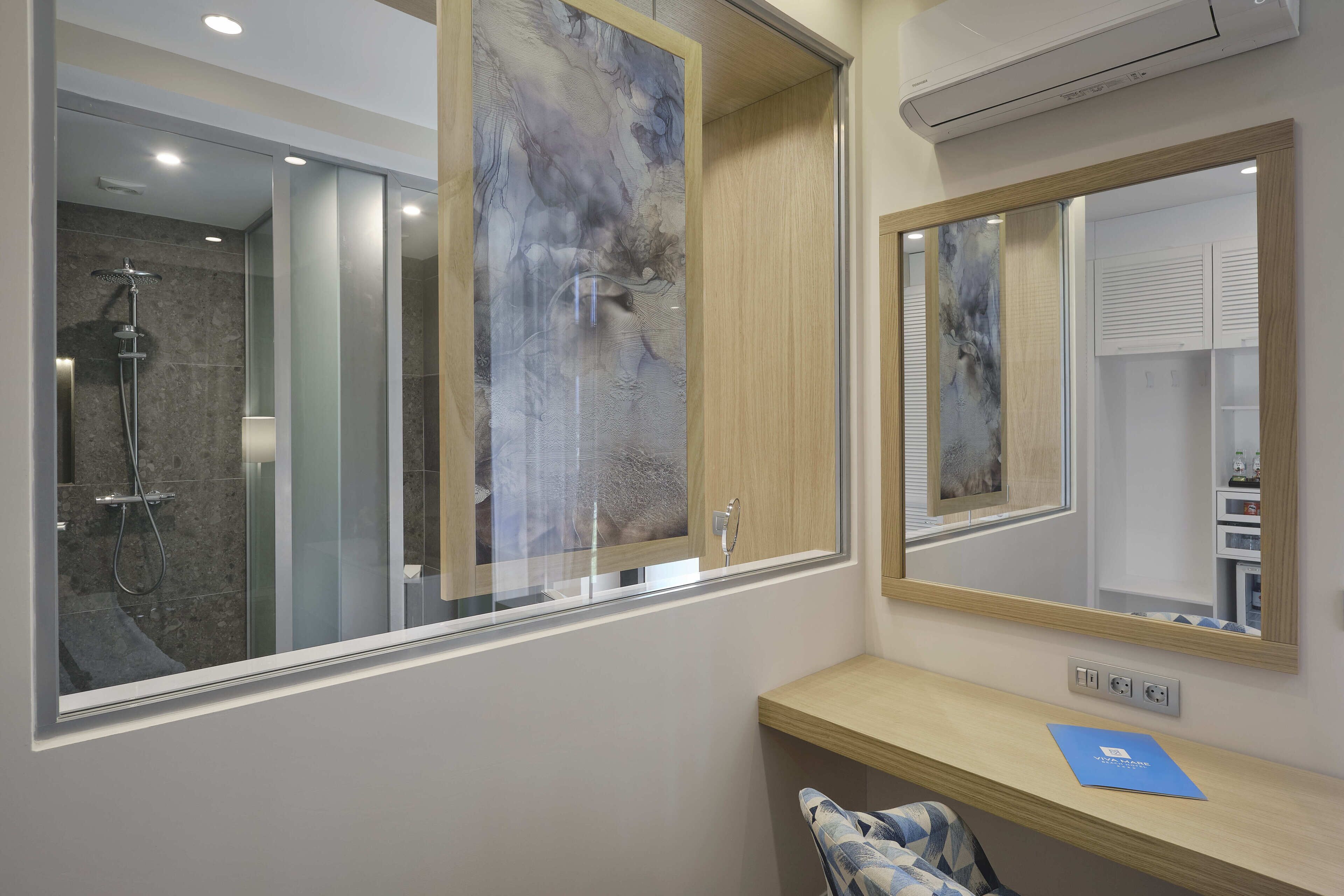 A modern bathroom with a glass shower enclosure, a wooden vanity with a mirror, and a blue folder on the counter.