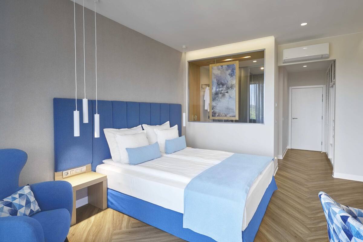 Una habitación de hotel moderna con una cama grande, un escritorio y una silla.