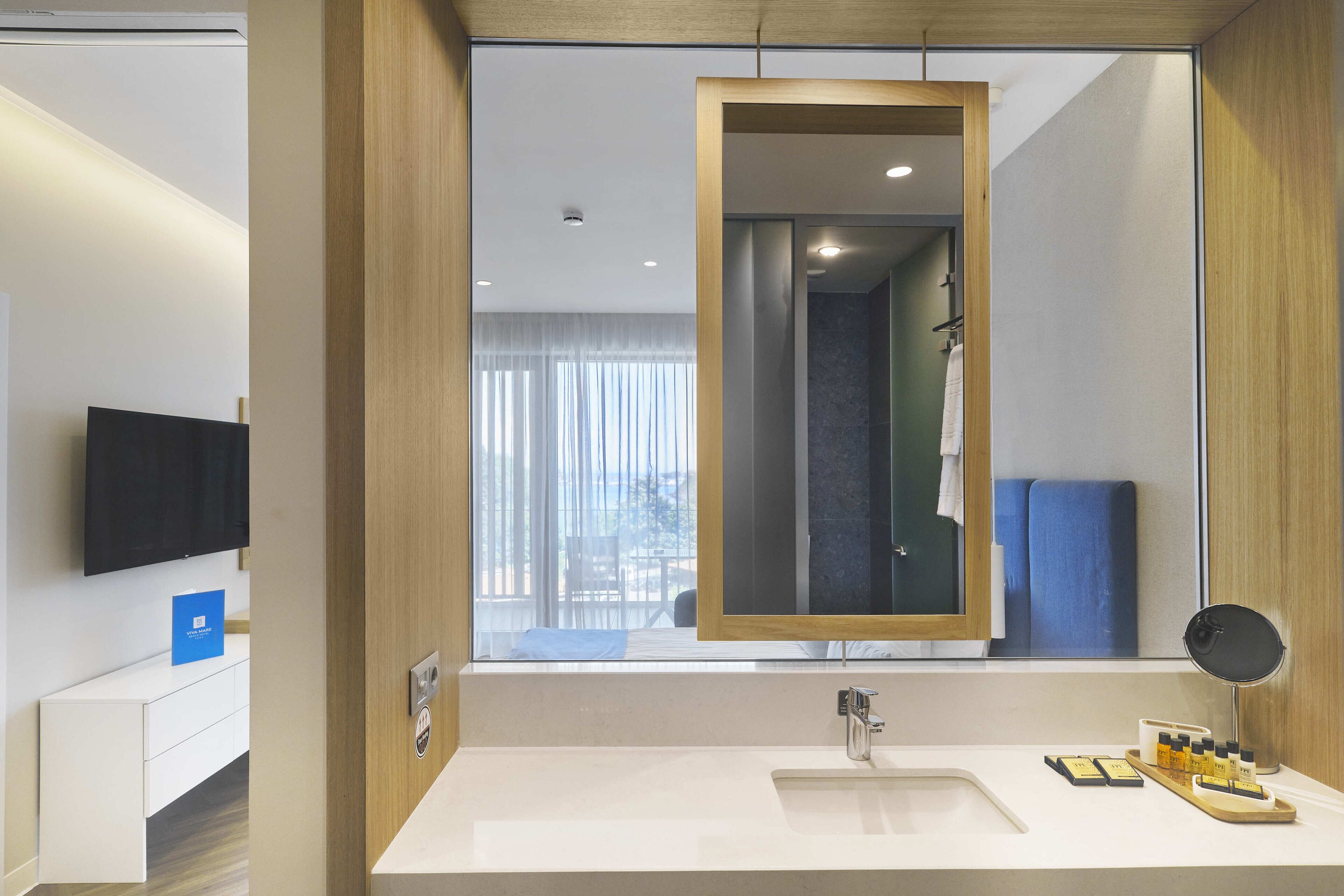 Un baño moderno con un espejo grande, un lavabo y artículos de aseo.