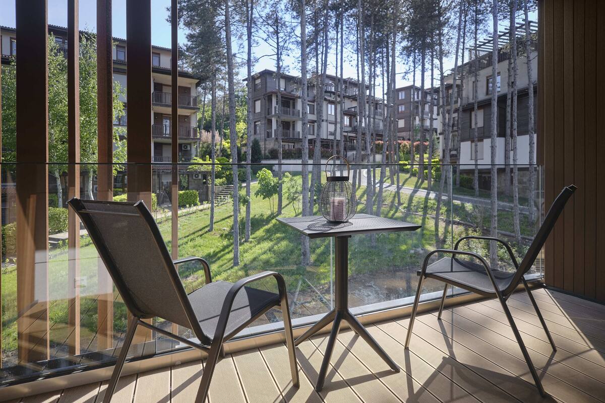 Un balcón con dos sillas y una mesa, con vistas a una zona residencial con varios edificios de apartamentos.