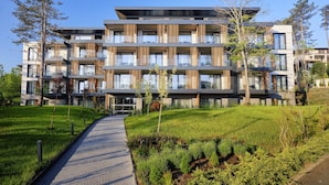 A modern multi-story residential building with balconies, a paved pathway, and a landscaped garden. - Viva Mare Beach Hotel (Sozopol)