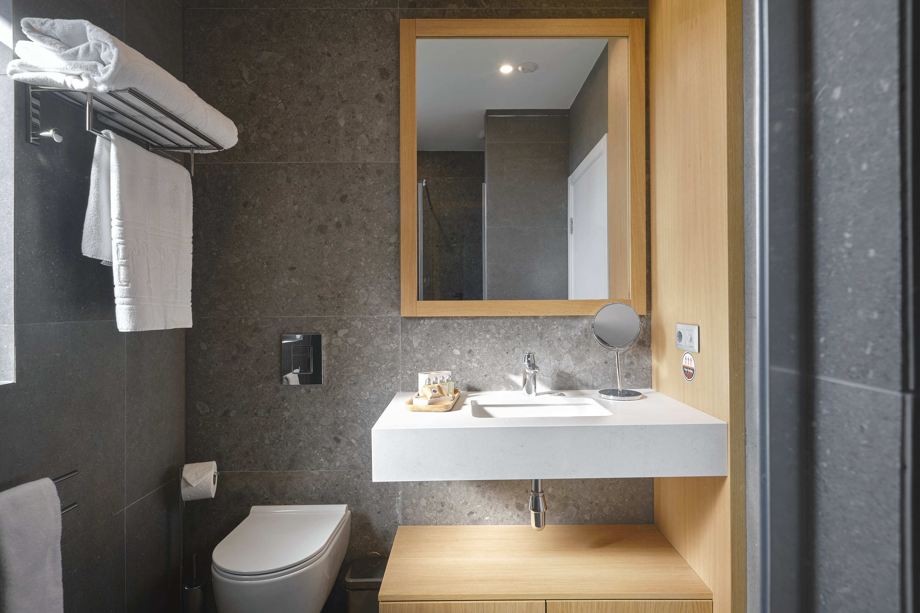 A modern bathroom with a white sink, a mirror, and a toilet.