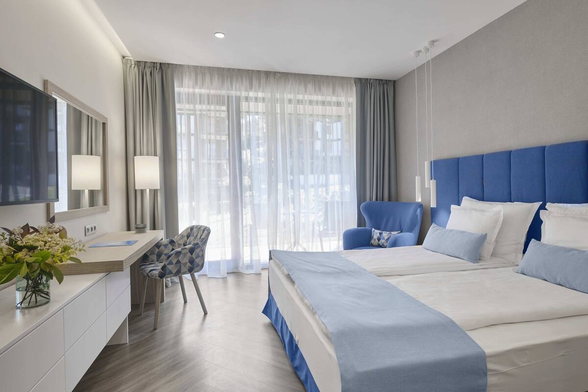 Una habitación de hotel moderna con una cama grande, un escritorio, una silla y un televisor.