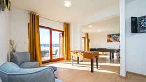 A room with a foosball table, a dartboard, and a pool table.