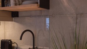 A modern kitchen with a built-in sink, a coffee machine, and a potted plant. - Home Again Kirkegata 30 (Stavanger)