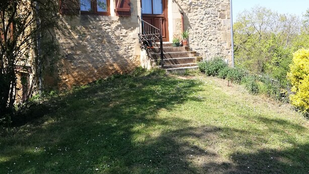 A stone building with a sloped roof, a wooden door, and a small set of stairs leading to a porch. - Studio (st crepin carlucet)