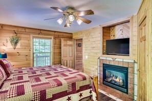 A cozy room with a bed, a fireplace, a ceiling fan, and a TV mounted on the wall. - 7mins to Smokies Secluded Mountain view Romantic sunsets with hot tub (Sevierville)