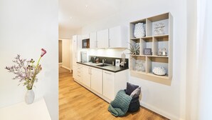 Una cucina moderna con mobili bianchi, un piano di lavoro in legno e una mensola a incasso con oggetti decorativi.