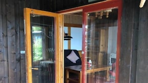 Eine Holzhütte mit einer Glastür, die in einen Essbereich mit Tisch und Stühlen führt.