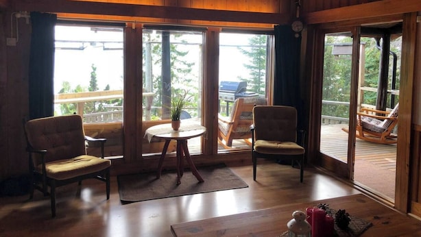 Ein gemütliches Zimmer mit Holzwänden und Holzböden, großen Fenstern und einer Deckenleuchte.