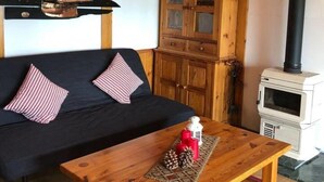 Ein gemütliches Wohnzimmer mit einem dunklen Sofa, einem Holztisch und einem weißen Herd.