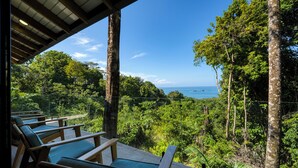 A covered outdoor seating area with wooden chairs and a view of the ocean. - NEWLY REMODELED GRAND OPENING PRICING
4 Bedroom villa (Uvita, Ballena, Puntarenas,)