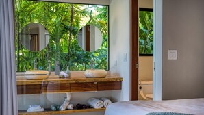 A modern bathroom with a large mirror, wooden vanity, and a view of lush greenery. - NEWLY REMODELED GRAND OPENING PRICING
4 Bedroom villa (Uvita, Ballena, Puntarenas,)