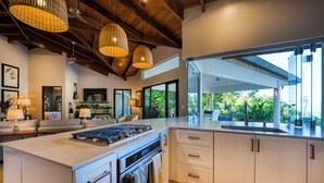 A modern kitchen with a central island, white cabinetry, and a large window offering a view of greenery. - NEWLY REMODELED GRAND OPENING PRICING
4 Bedroom villa (Uvita, Ballena, Puntarenas,)