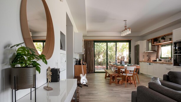 Una cocina moderna con armarios blancos, un comedor con mobiliario de madera y un ventanal que proporciona luz natural.