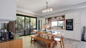 Una cocina moderna con una mesa y banco de madera, armarios blancos y un ventanal con vistas al exterior.