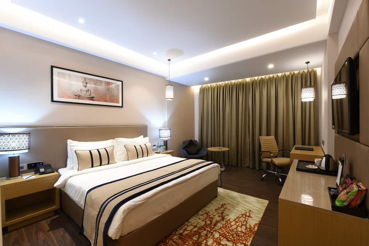 A modern hotel room with a large bed, bedside tables, a desk, and a chair.