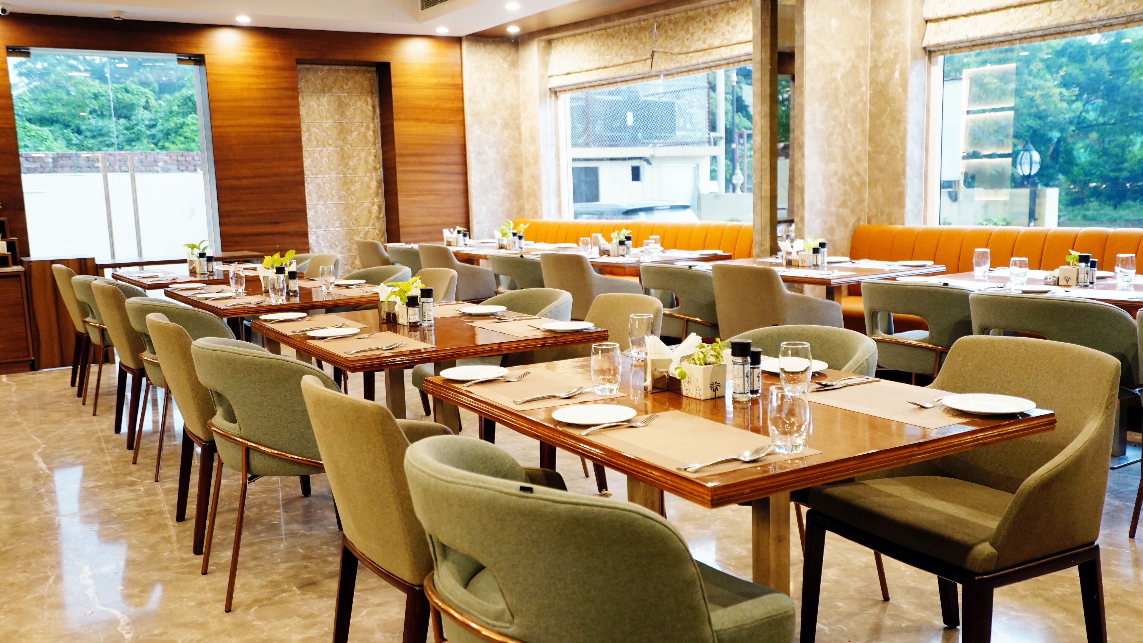 Ein Restaurant mit mehreren Esstischen, gedeckt mit Tellern, Besteck und Gläsern.