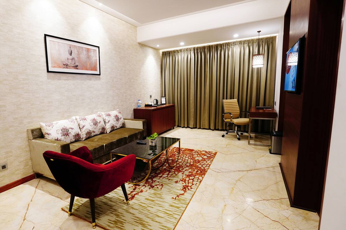 A modern living room with a sofa, a red chair, a coffee table, and a TV.