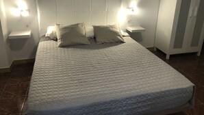 A bed with a quilted mattress, two patterned pillows, and two bedside lamps. - TAMONANTE HOSTEL (Gran Tarajal)