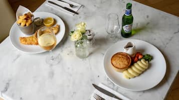 Una mesa de comedor con platos de comida, una botella de cerveza y un salero.