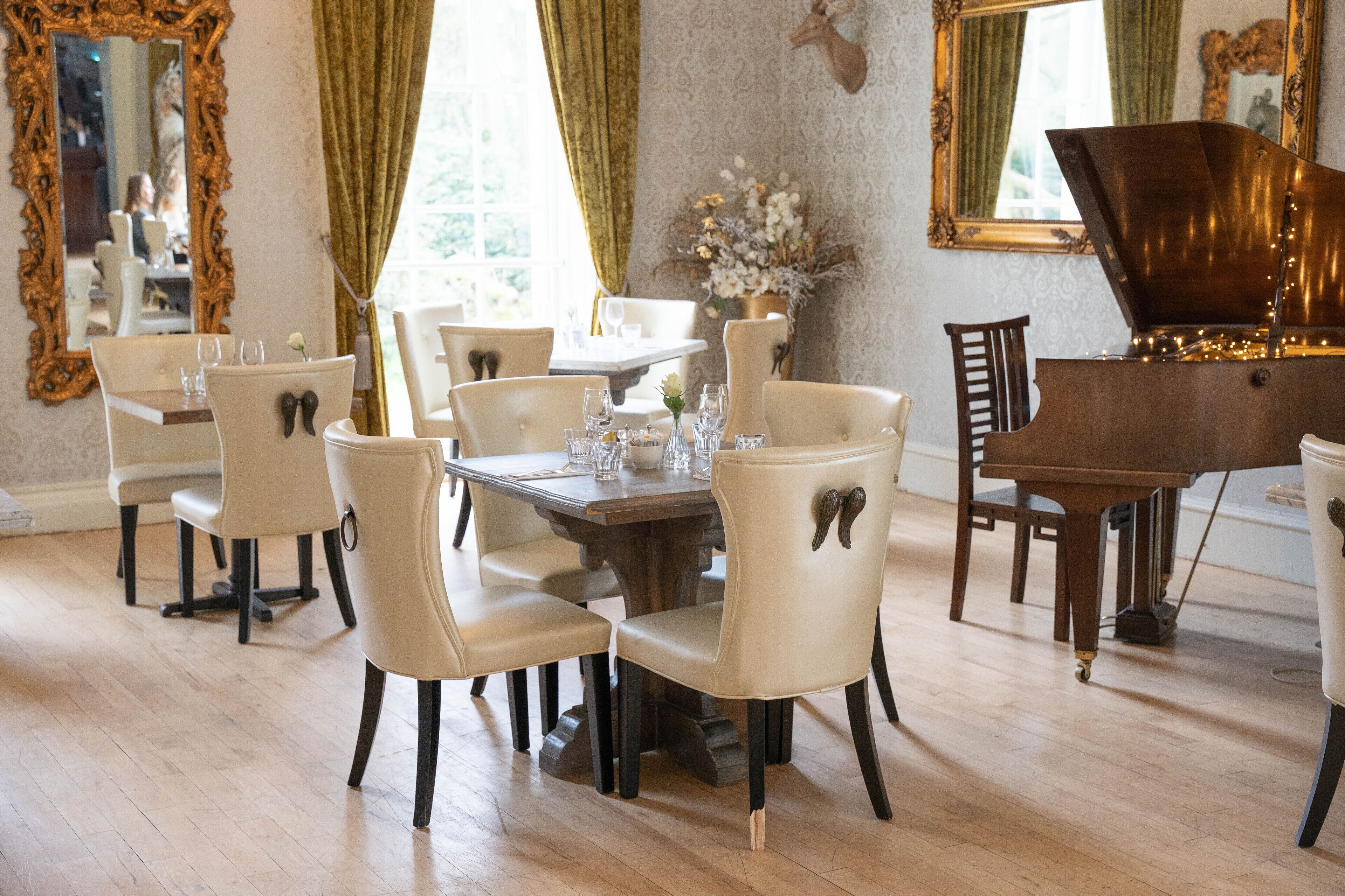 A dining area with a wooden table, white chairs, and a grand piano.