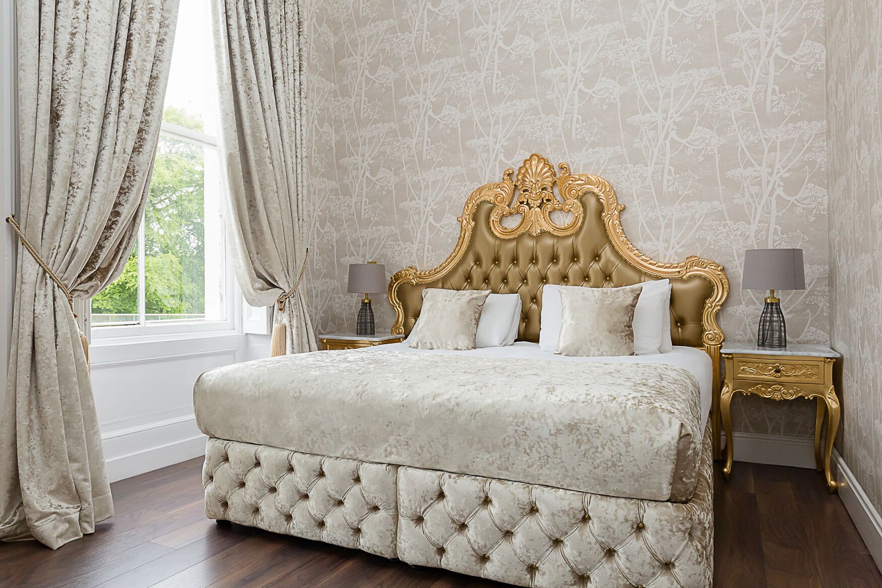Une chambre à coucher luxueuse avec un lit capitonné, une tête de lit décorée et des tables de chevet assorties.