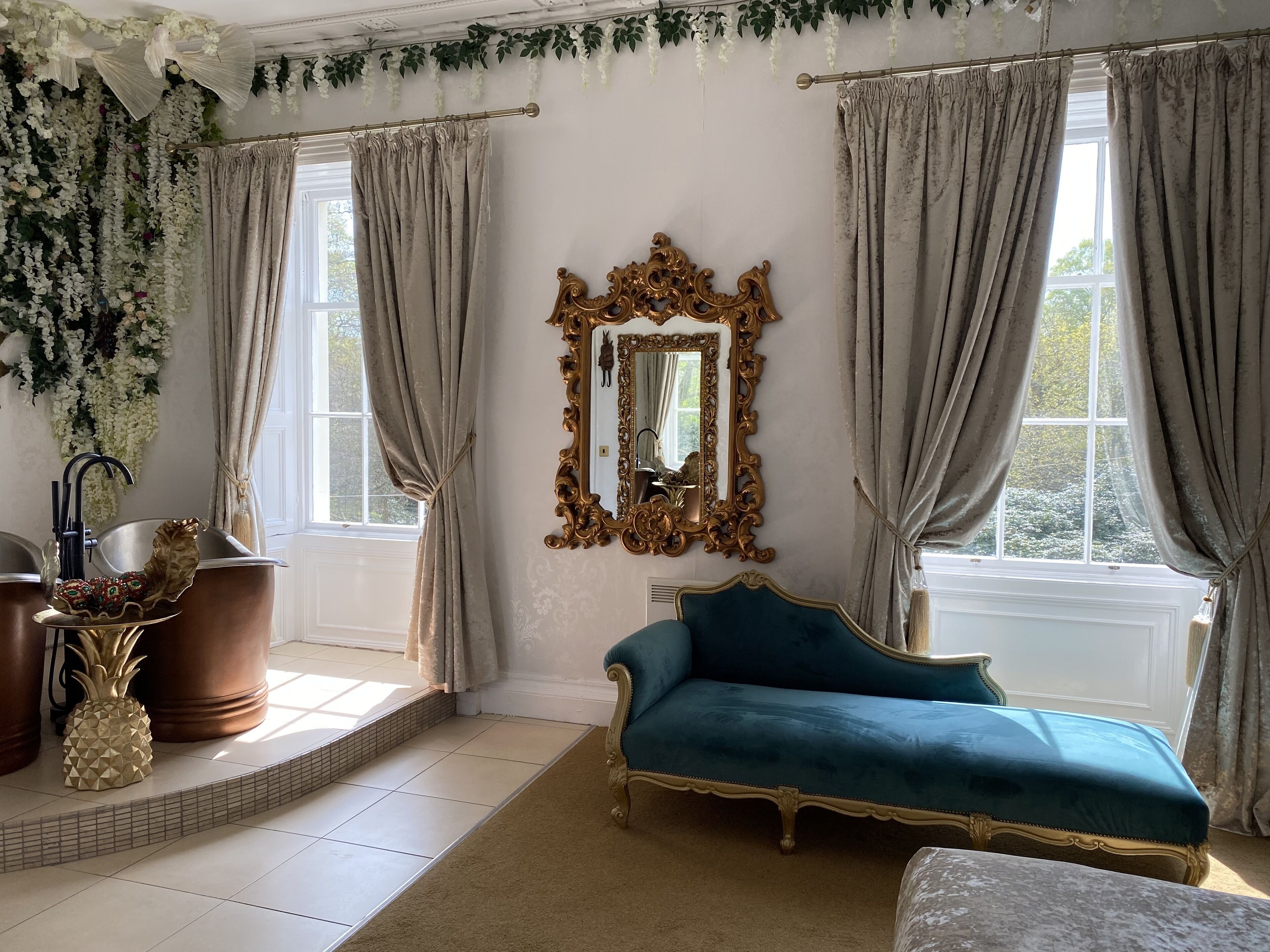 A room with a large mirror, a blue sofa, and a pineapple decoration.