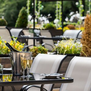 An outdoor dining area with a table set for two, featuring a champagne bottle and glasses. - Rainhill Hall (Liverpool)