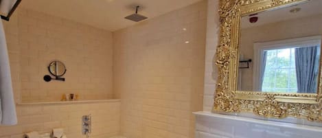 A bathroom with a toilet, bathtub, and sink, featuring a large ornate mirror and a small window.