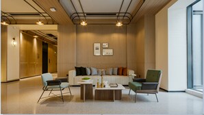 A modern lobby with a sofa, chairs, a coffee table, and pendant lighting.