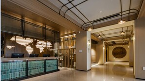 A modern hotel lobby with a reception desk, a world map mural, and a circular wall feature.