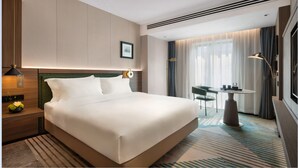 A modern hotel room with a large bed, a small table, and a chair.