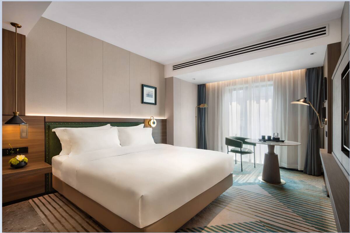 A modern hotel room with a large bed, a small table, and a chair.