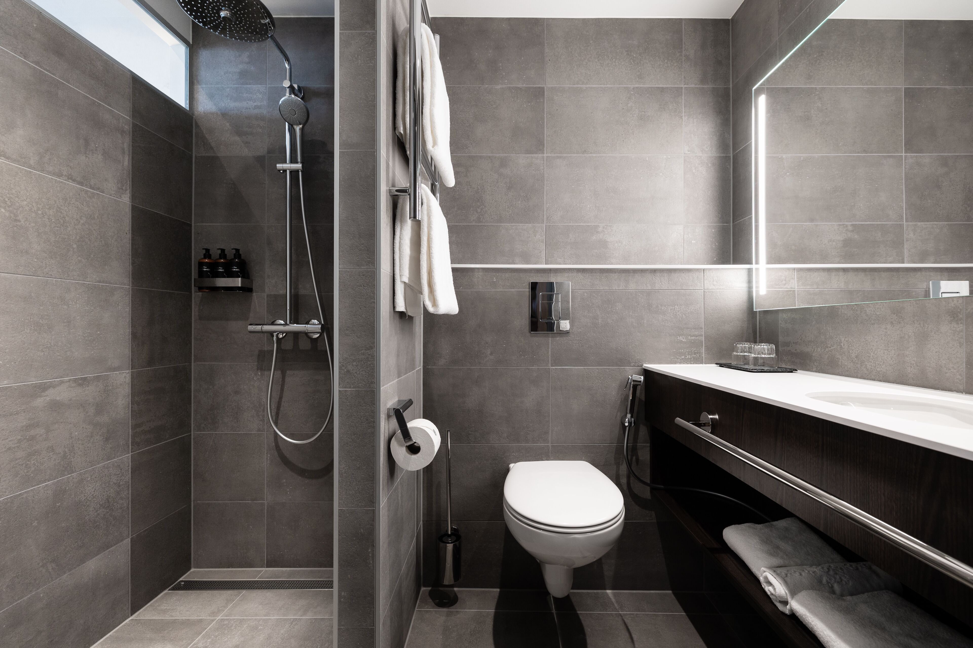 A modern bathroom with a shower, toilet, and vanity.