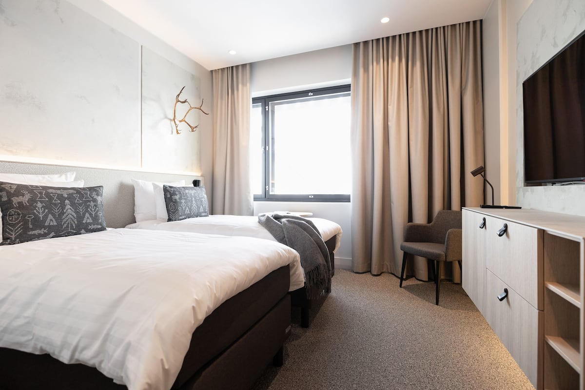 Ein modernes Hotelzimmer mit einem großen Bett, einem Schreibtisch und einem Fernseher.