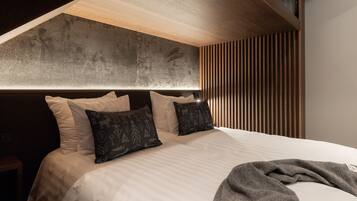 A modern bedroom with a large bed, a headboard with a textured design, and a wooden slat wall.