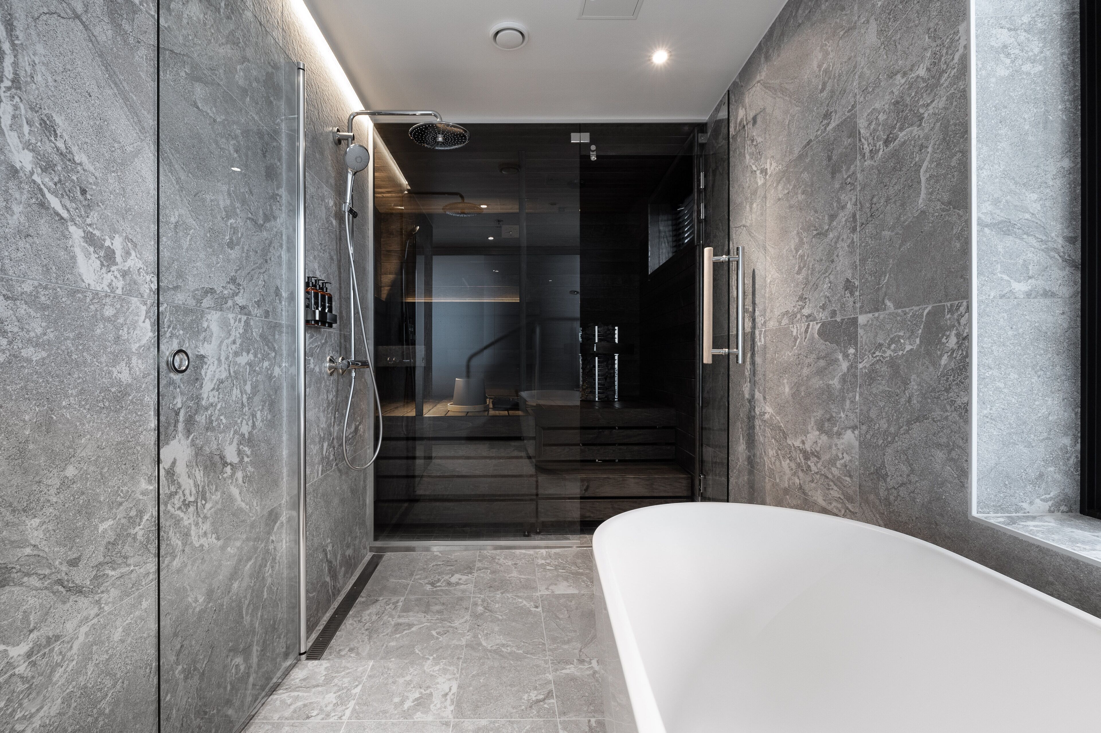 Ein modernes Badezimmer mit einer Duschkabine aus Glas, einer Badewanne und einer Wendeltreppe aus dunklem Holz.