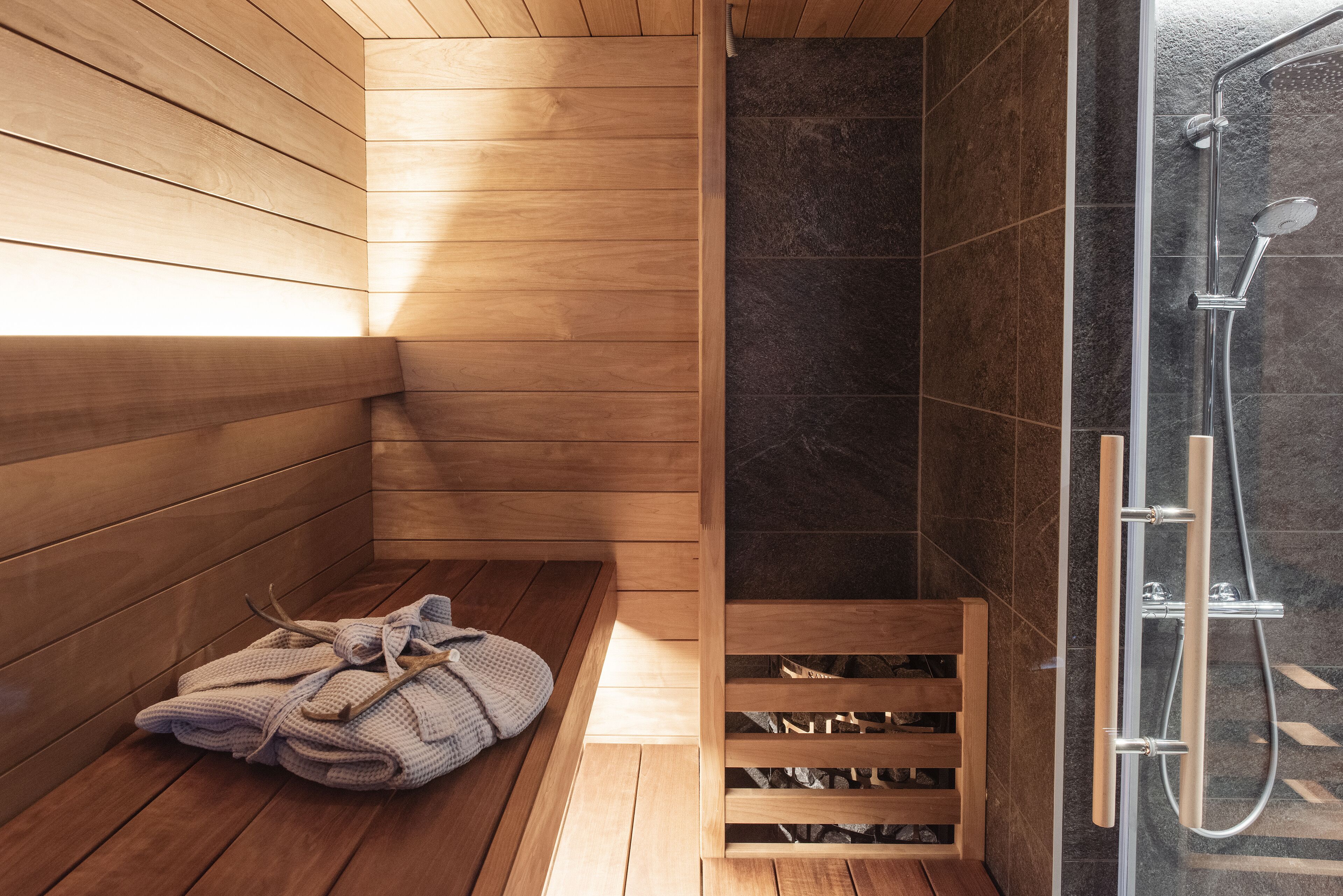 A sauna with wooden benches and a bench with towels.
