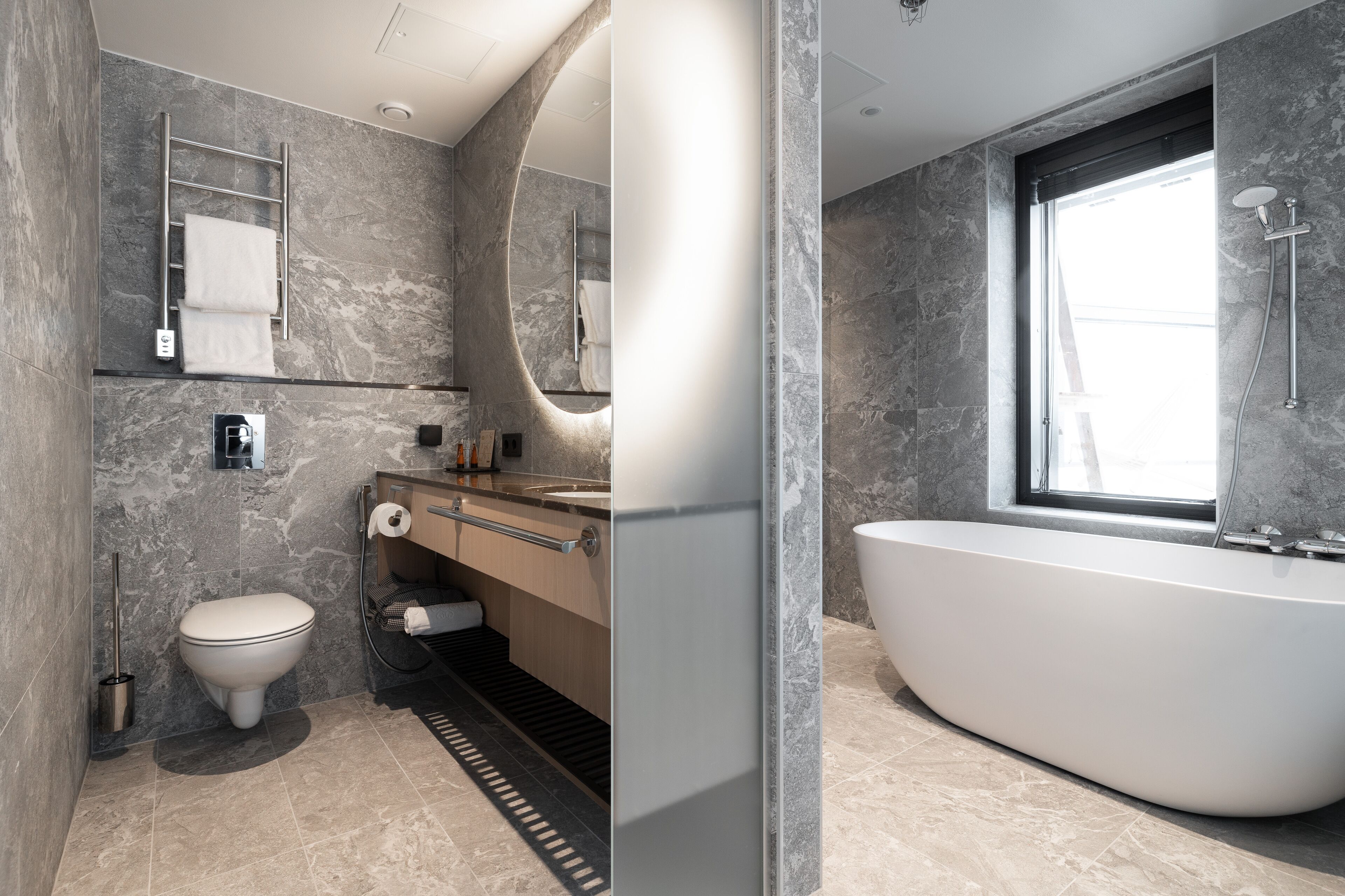 A modern bathroom with a freestanding bathtub, a toilet, and a vanity with a mirror.