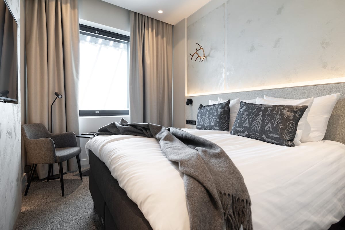 Ein modernes Hotelzimmer mit einem großen Bett, einem Schreibtisch und einem Stuhl.
