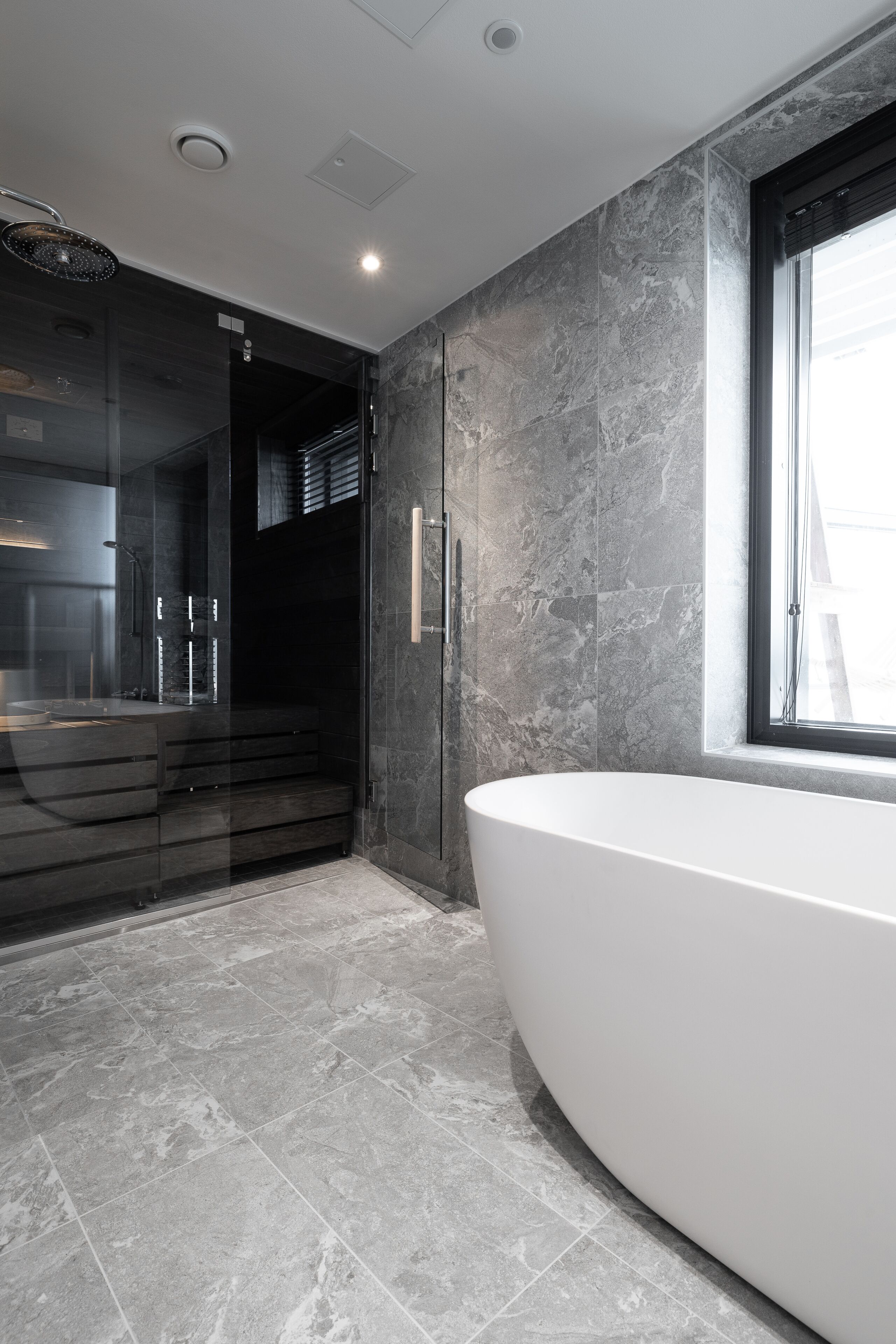 A modern bathroom with a freestanding bathtub, a glass-enclosed shower, and a large window.