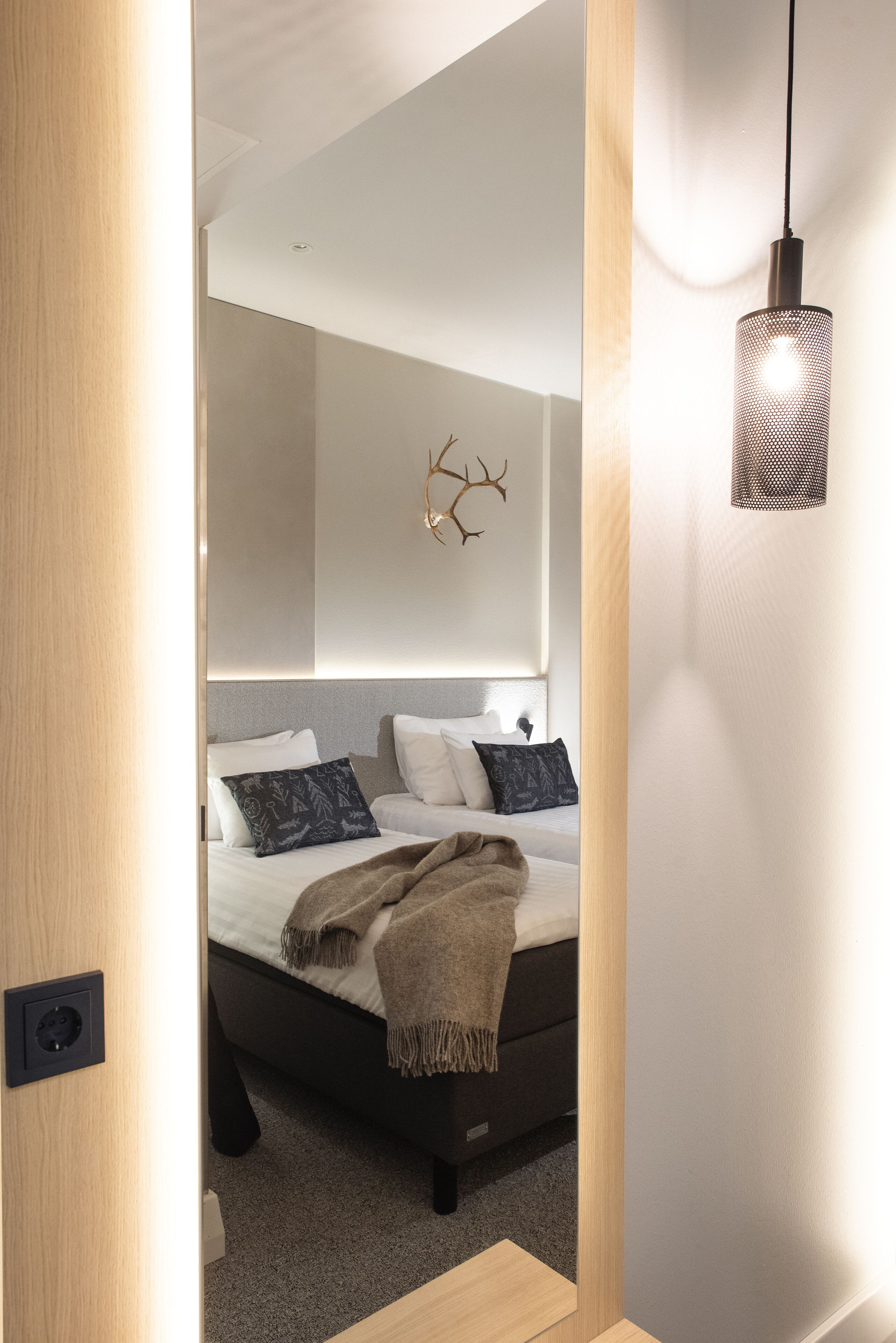 A modern bedroom with a bed, a wall-mounted light fixture, and a decorative wall piece.