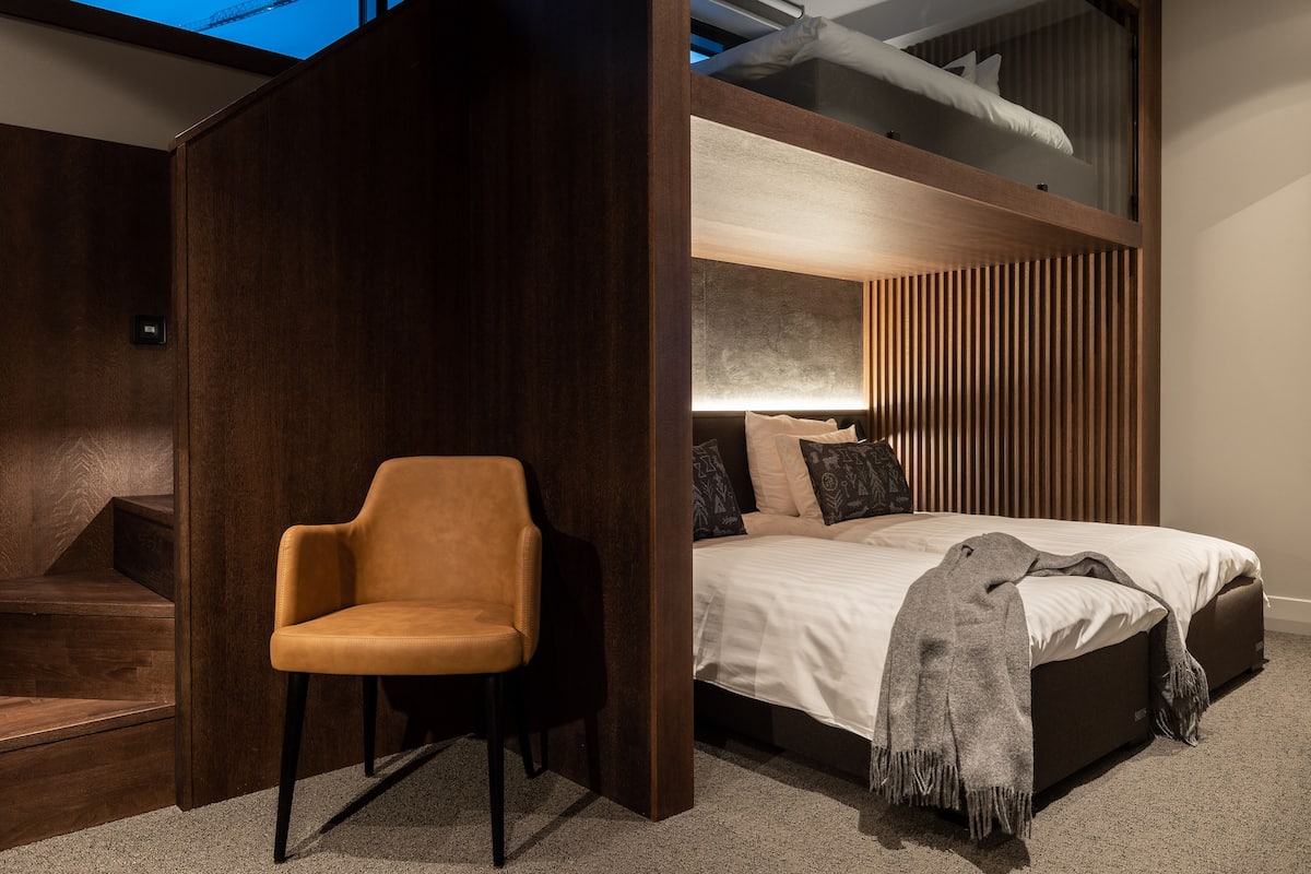 Ein modernes Schlafzimmer mit einem Bett, einem Sessel und einer Holzwand.