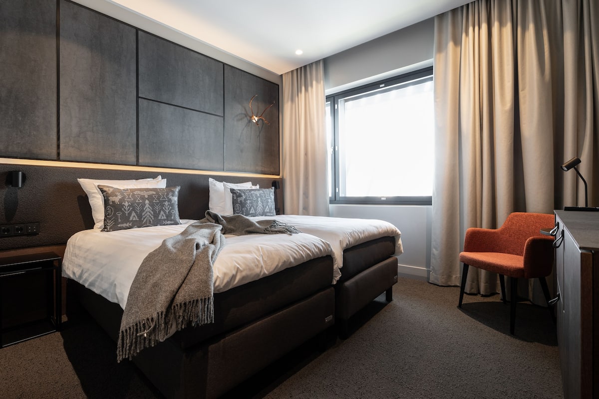 Ein modernes Hotelzimmer mit einem großen Bett, einem Schreibtisch und einem Stuhl.