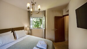 Une chambre d’hôtel avec un lit, un lustre, une fenêtre et une armoire.