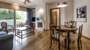 Un salon moderne avec une cheminée, un coin repas avec des chaises en bois et une grande fenêtre donnant sur un espace verdoyant.