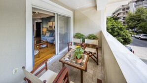 Un balcon avec une table à manger, des chaises et des plantes en pot.