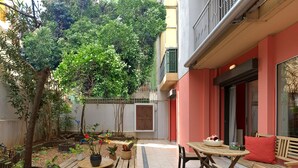 Ein Patio mit Holztischen und -bänken, umgeben von Blumentöpfen und einem kleinen Garten.