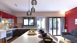 Eine moderne Küche mit Kochinsel, roten Schränken und einem Essbereich mit grauem Sofa.